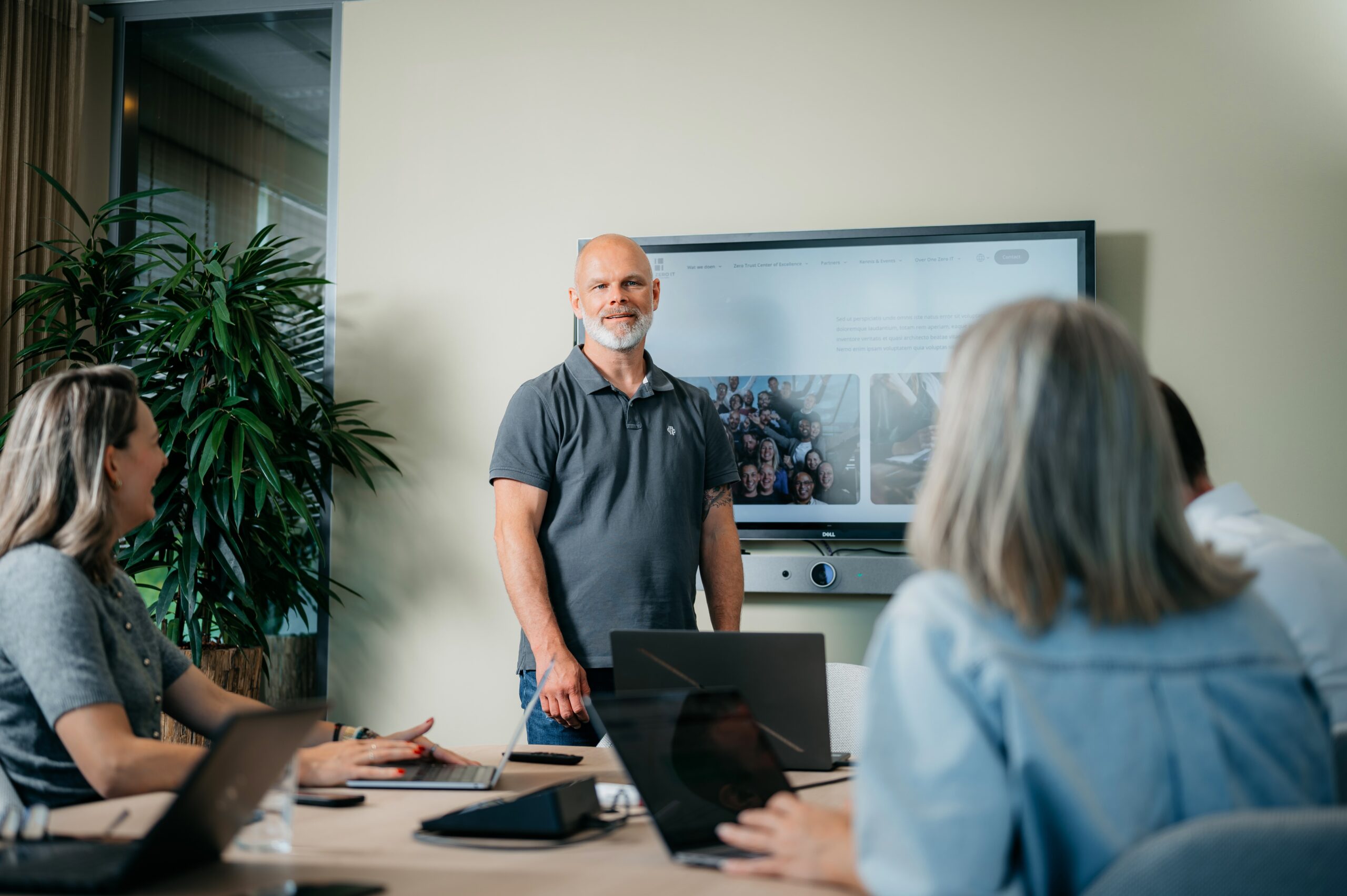 Man standing in front of a television screen presenting a Zero Trust project to fellow project members